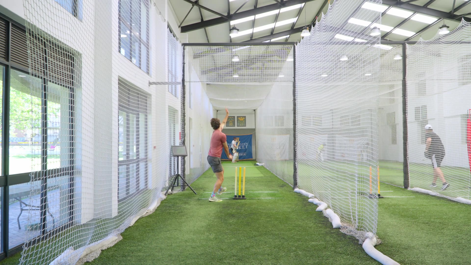 Bowler delivering in a CricHit net with the camera set up alongside